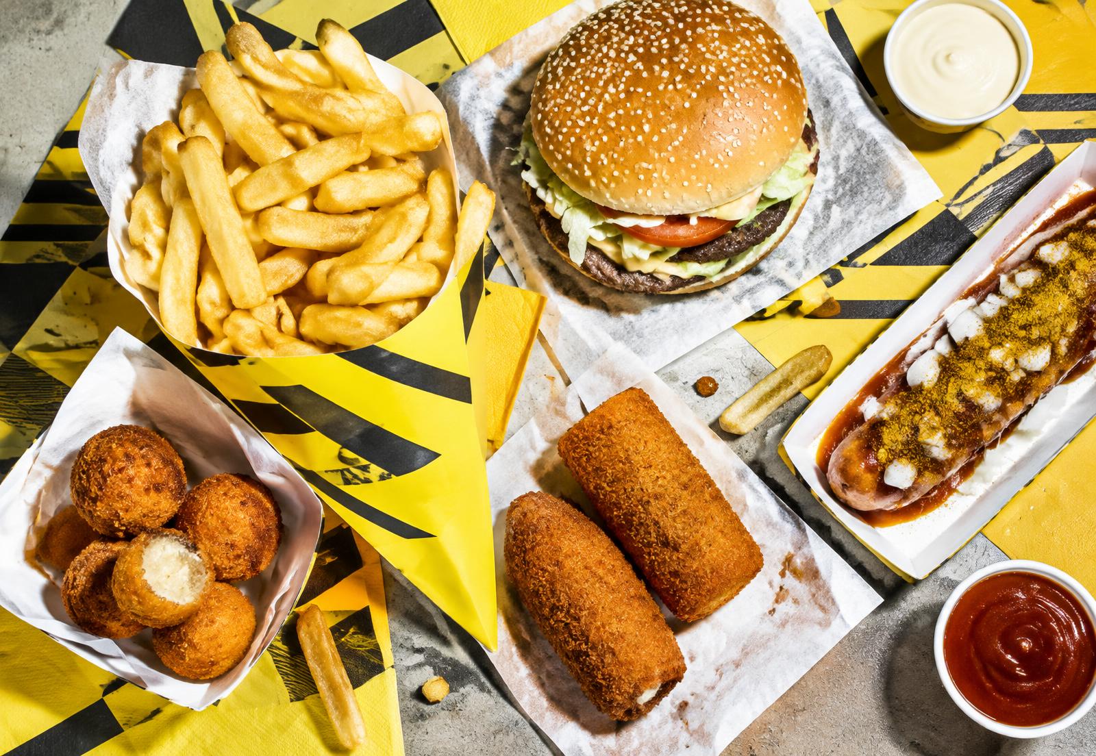 Een feestelijke tafel vol frieten, burgers en snacks